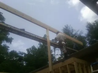 Carpenter setting a ridge beam over a new addition frame — Ice Dam Removal by Roofing Brothers in Lacona