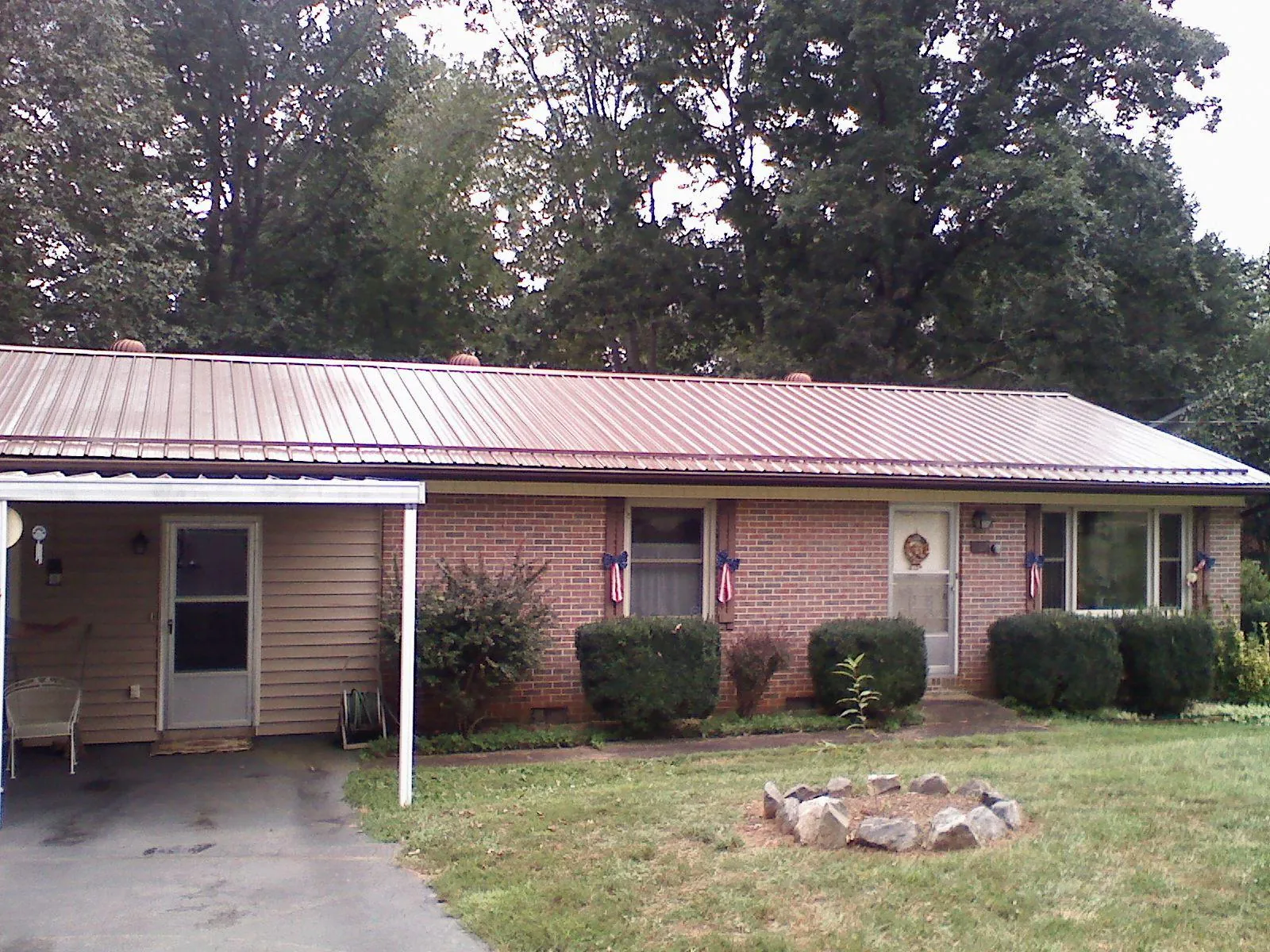 Bronze metal roof and carport on a brick ranch home — Roof Repair work by our crew in Lacona